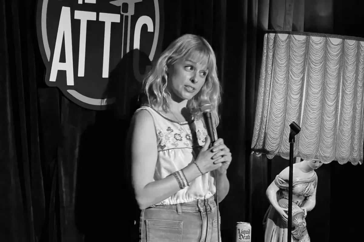Comedian speaks into a mic on stage at The Attic