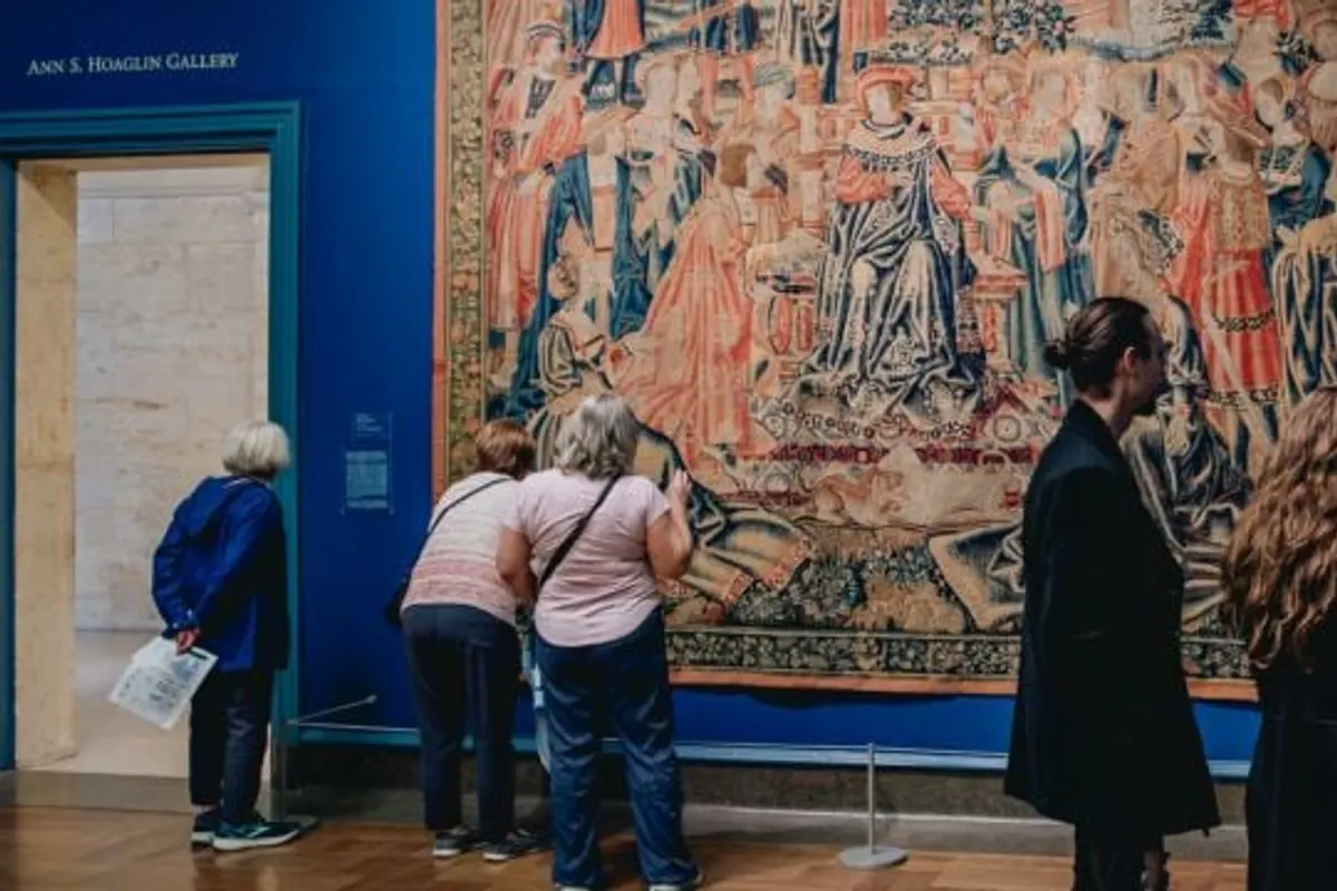 Visitors examine a tapestry in the museum's blue gallery