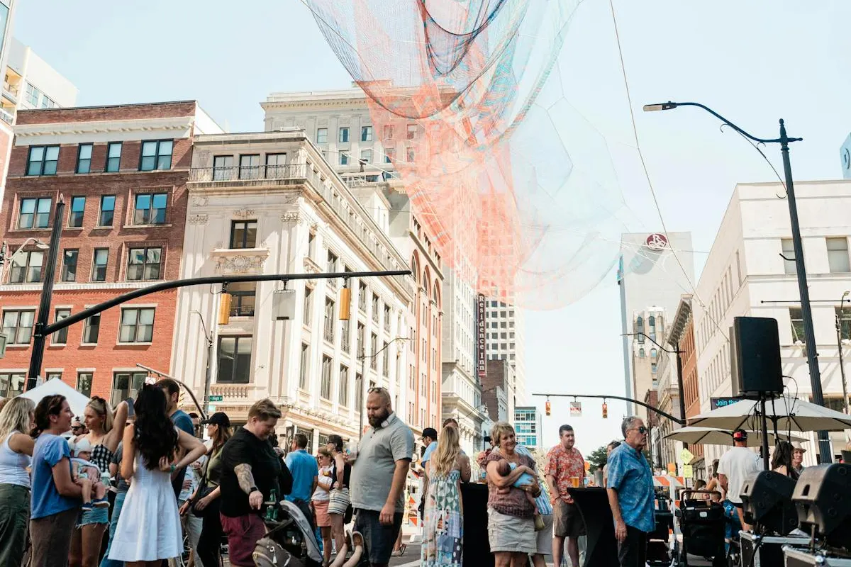 Crowd gathers beneath the downtown sculpture at dusk