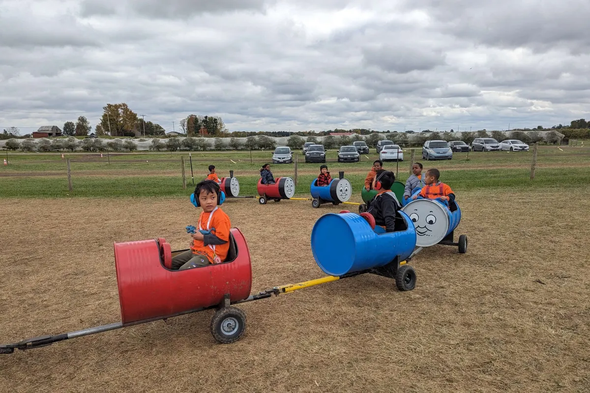 Kids ride barrel-train cars at the fall farm