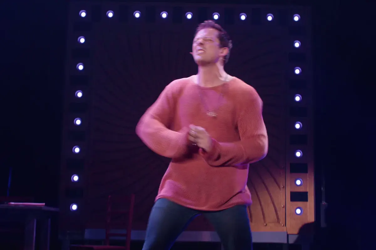 Actor performs under stage lights in a musical