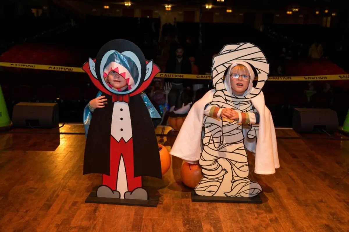 Two kids in Halloween photo cutouts on the Palace Theatre stage