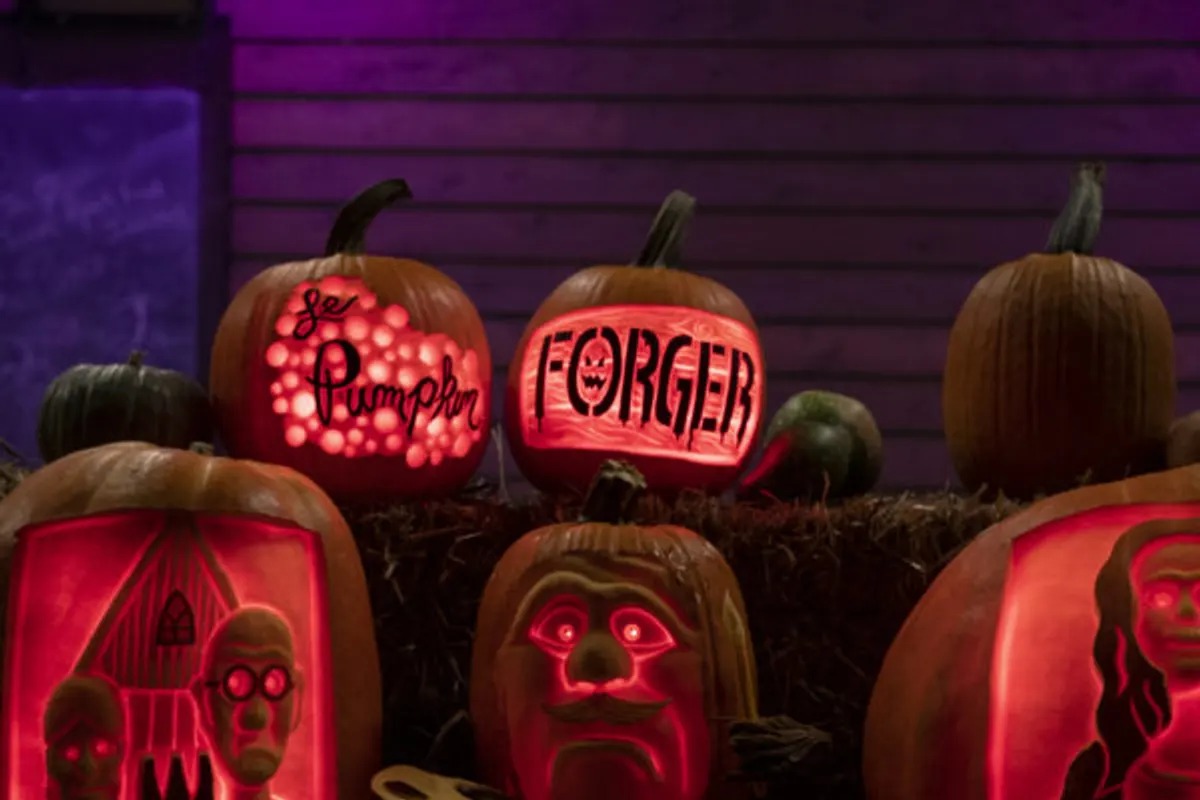 Glowing carved pumpkins with art-themed designs on hay bales