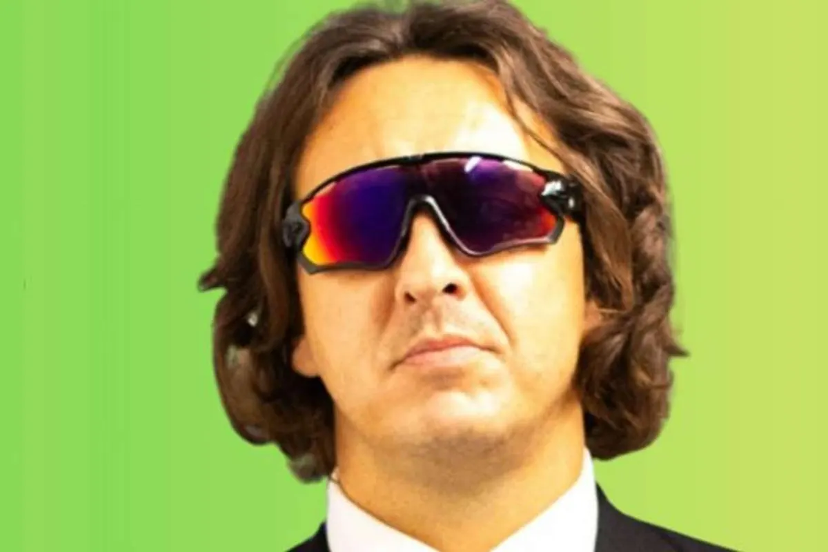 Man with shoulder-length hair wearing wraparound sunglasses and a suit
