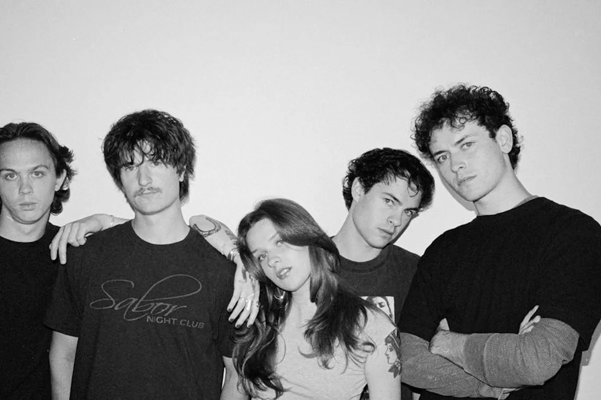 Black and white portrait of five band members posed against a plain wall
