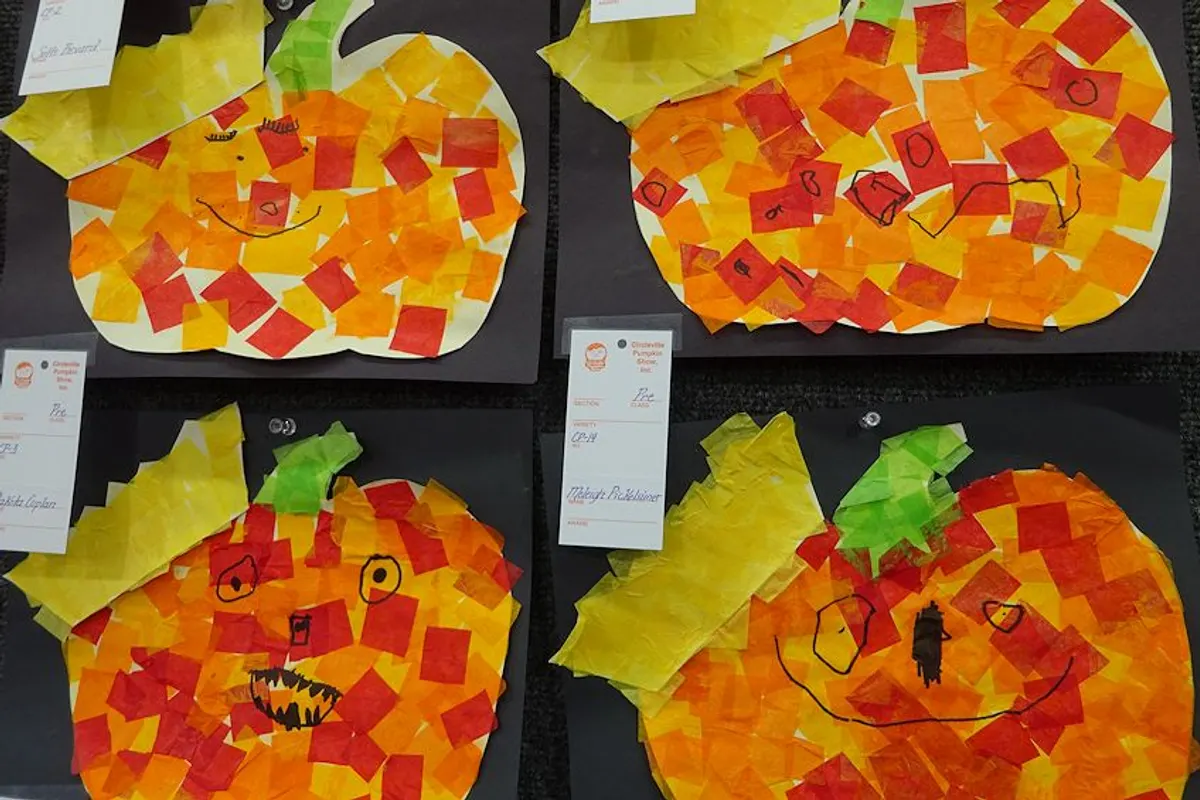 Children's tissue-paper pumpkin crafts displayed on a wall