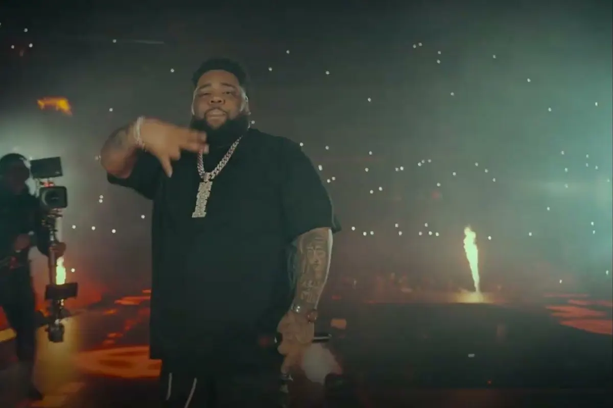 Rapper performing on stage with a camera operator behind him