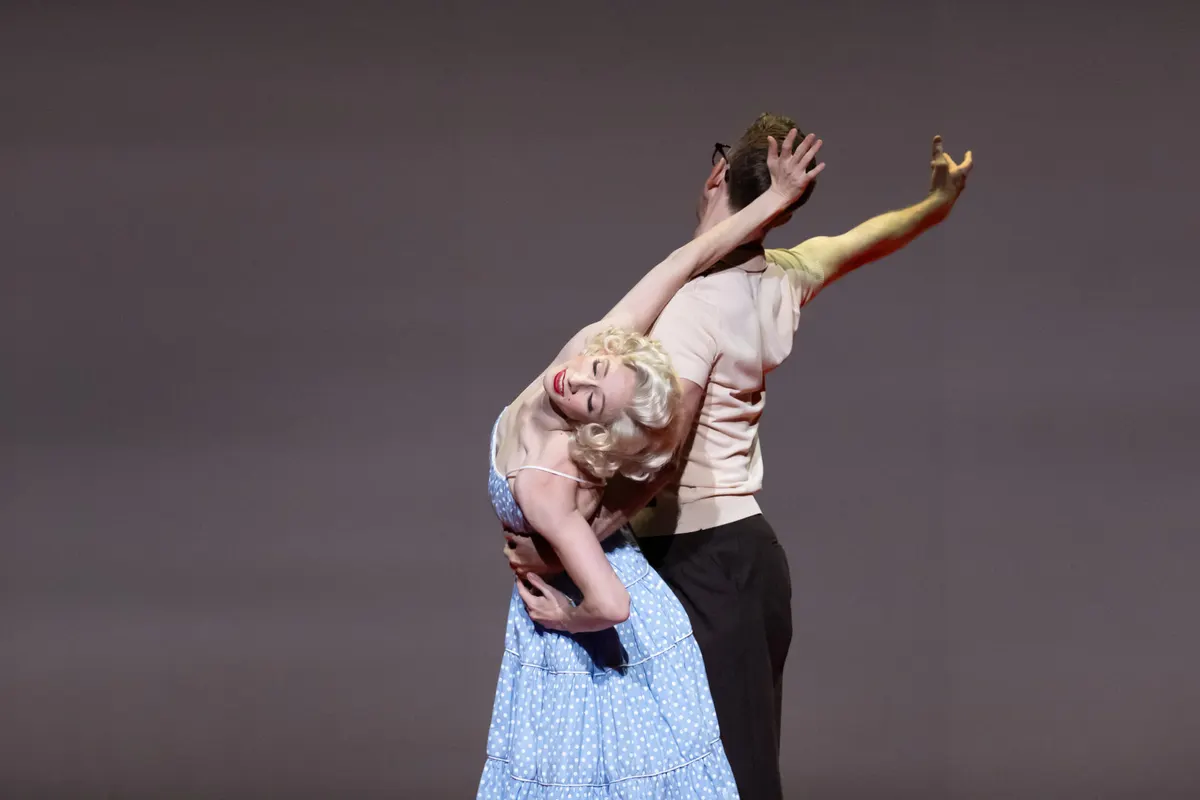 Two dancers in an embrace, one in a blue polka dot dress