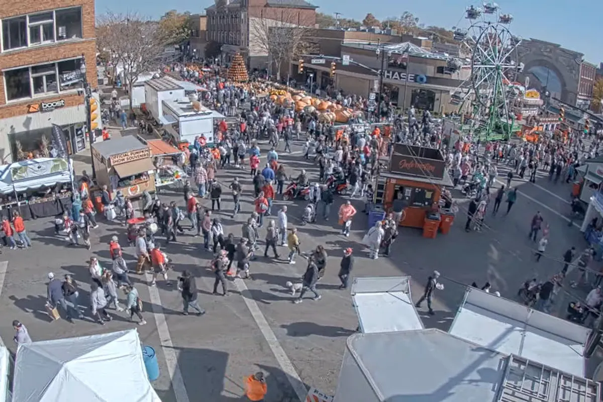 Crowd fills a downtown street with food stands and a Ferris wheel