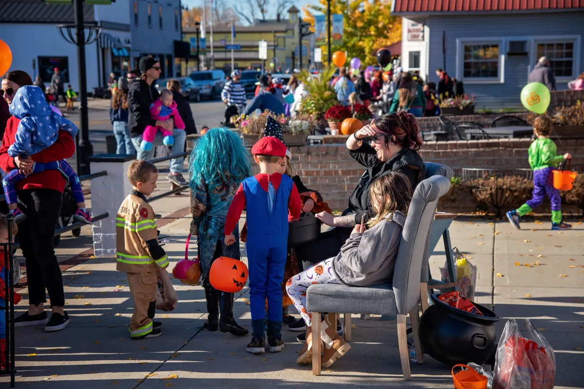 Children in Halloween costumes with pumpkin buckets on a Hilliard sidewalk