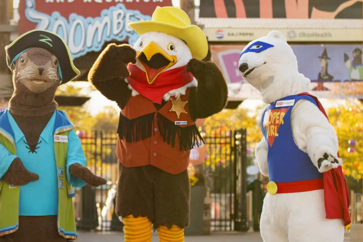 Zoo mascots in Halloween costumes in front of the zoo entrance