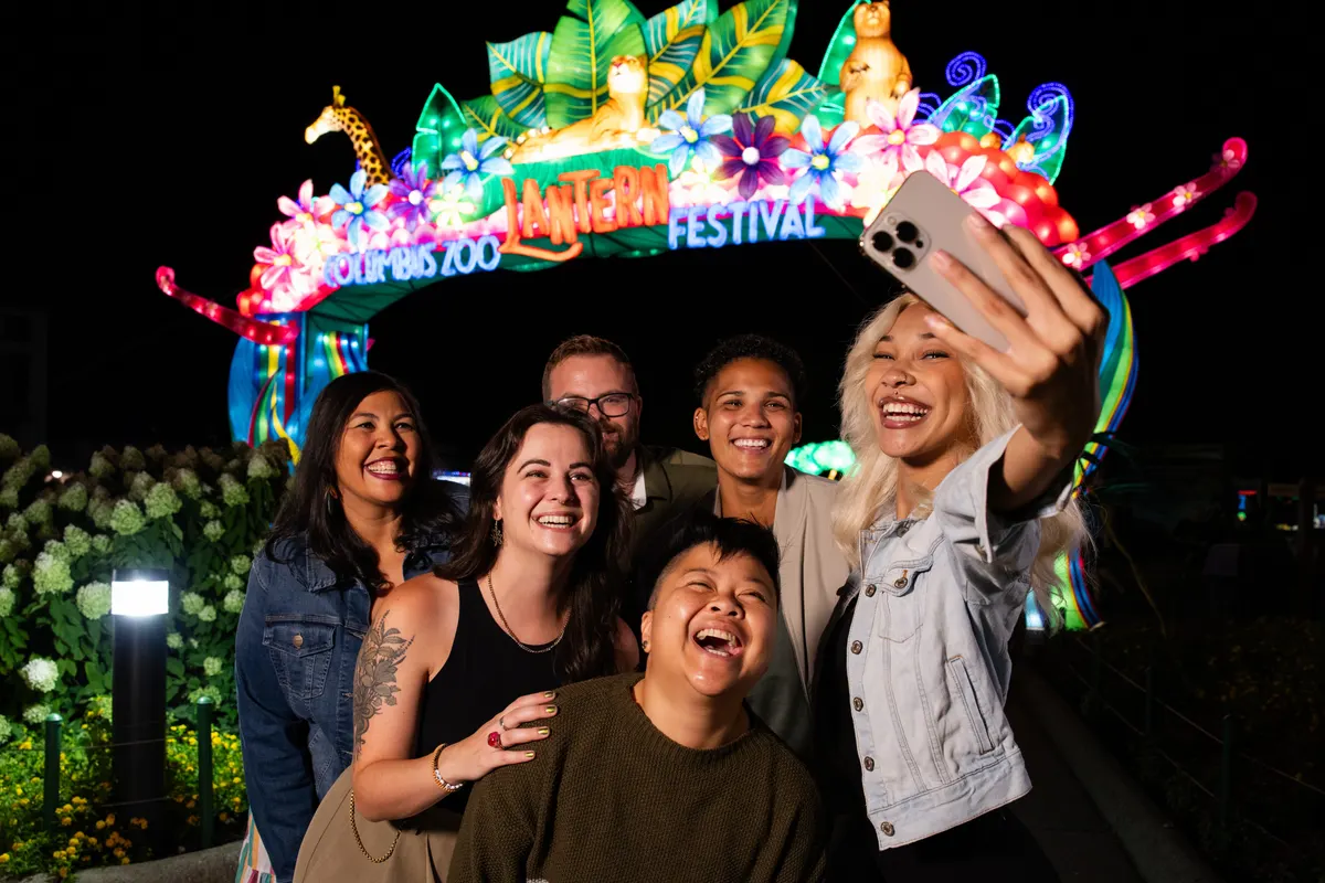 Friends take a selfie under the glowing Columbus Zoo Lantern Festival arch