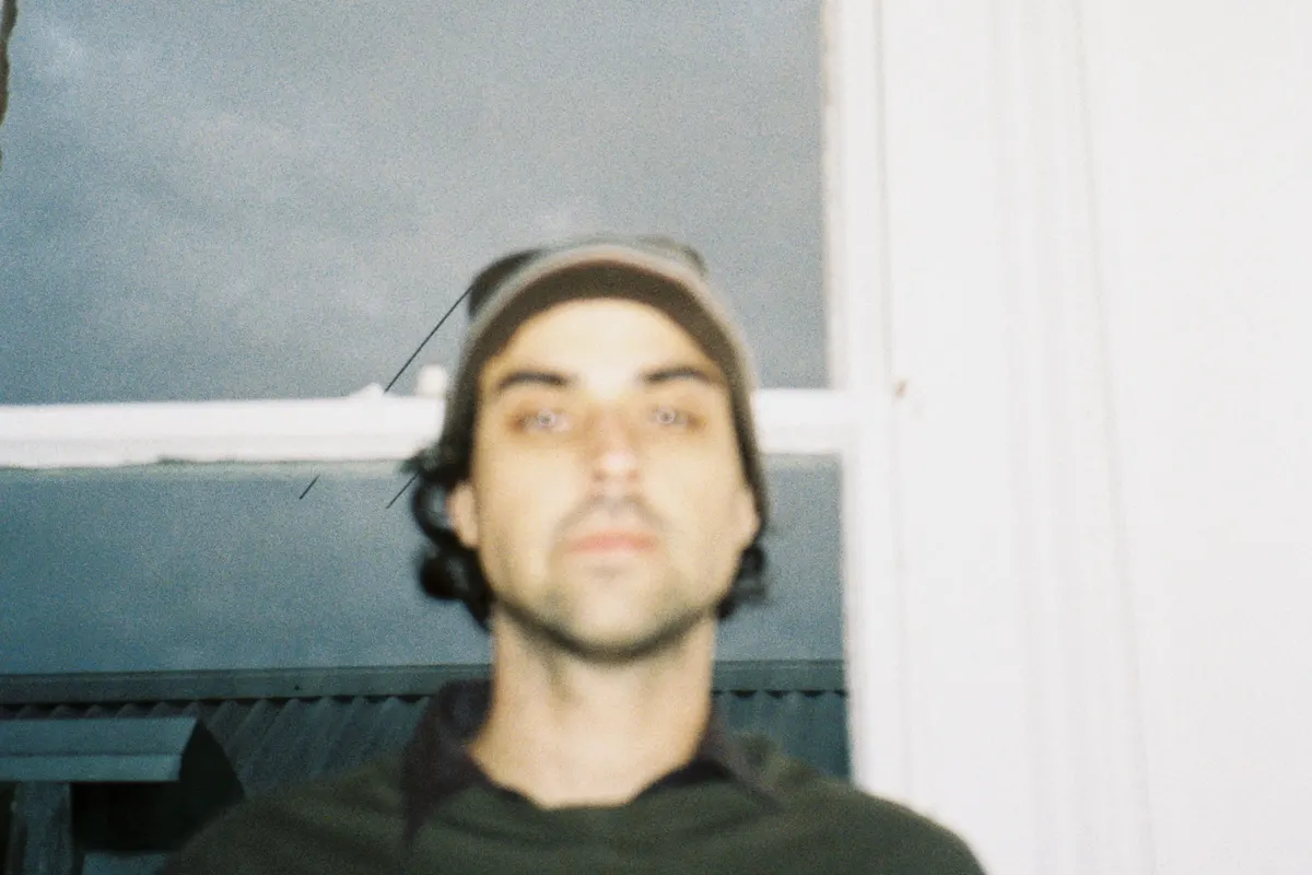 Film-style portrait of a man in a cap by a window